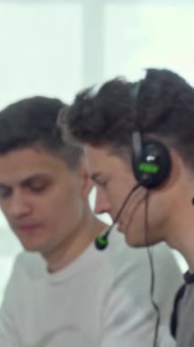 İki odaklanmış erkek çağrı merkezi operatörü, biri derin düşüncelere dalmış, diğeri dikkatle dinliyor, takım çalışmasından ve konsantrasyondan oluşan dinamik bir atmosfer yaratıyor. Bu canlı sahne, modern bir çalışma alanındaki işbirliğinin özünü vurgular.