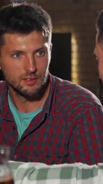 Sıcak, davetkar bir barda, biri genç ve çekici iki erkek arkadaş, diğeri ise daha çok soğuk bira eşliğinde içten bir kahkaha paylaşıyor. Canlandırıcı konuşmaları ve neşeli ifadeleri, gevşemek için mükemmel, canlı bir atmosfer yayıyor.