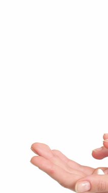 Bu yakın plan çekimde genç beyaz bir kadın nazikçe avuçlarına krem sürüyor, narin parmaklarını nazikçe hareket ettiriyor. Serin beyaz arka plan yumuşak ellerini vurguluyor, rahatlamanın ve kendine bakmanın huzurlu atmosferini anımsatıyor.