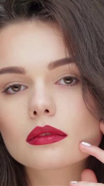 Bu büyüleyici portre, beyaz saçlı, dalgalı esmer ve koyu kırmızı dudaklı parlak siyah bir fon karşısında kendine güvenen genç bir kadını gözler önüne seriyor. Kusursuz cildi ve yüzüne dokunuşu bir zarafet ve modern hissi uyandırıyor.