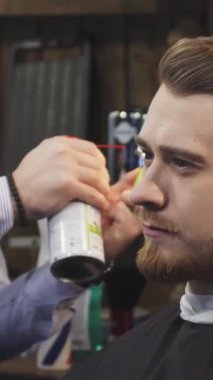 Yakışıklı, sakallı bir adamın büyüleyici yakın çekimi, yetenekli bir berber gibi sırıtarak ateşli bir saç tedavisiyle havada heyecan yaratır. Titrek alevler şık berber dükkanını aydınlatıyor, sanatını ve hassasiyetini sergiliyor.