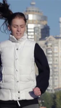 Odaklanmış bir kız kollarını nefes kesen bir şehir siluetine doğru uzatıyor. Forma olan bağlılığını somutlaştırıyor. Sonbahar yapraklarının canlı renkleri ve parlak mavi gökyüzü enerjik bir zemin oluşturuyor, sağlıklı ve aktif bir yaşam tarzına ilham veriyor.