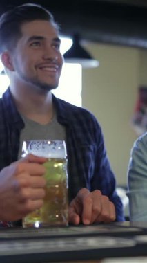 Bir futbol maçının heyecanını yaşayan üç coşkulu genç adam canlı bir barda coşkulu bir kadeh kaldırarak kadeh kaldırıyor. Bu unutulmaz dostluk anını paylaştıkları için, hayat dolu atmosfer kahkaha ve dostlukla dolu.