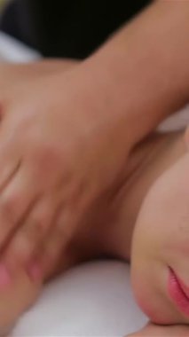 Yüzükoyun yere uzanmış, beyaz havlulara sarılmış, huzurlu bir rahatlama vahası yaratarak, yetenekli bir kadın terapist omuzlarını nazikçe ovuyor. Yumuşak ışıklandırma ve sakinleştirici atmosfer mutluluk dolu deneyimi güçlendirir.