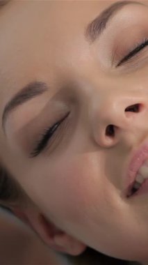 Uzman bir masaj terapisti dingin, genç, beyaz bir kadına huzur saçan mutlu yüz ifadesi ile canlandırıcı bir cilt masajı yapıyor. Yakın plan çekimler kadınların parlayan ciltlerini ve rahat tavırlarını ön plana çıkarıyor.