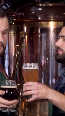 İki tutkulu bira imalatçısı, biri şık sakallı, diğeri canlı ekose gömlekli, bardaklarını altın ve karanlık zanaat birasıyla doldurmuş, bira içme sevdalarını kutluyorlar. Bira fabrikasının sıcak parıltısı,