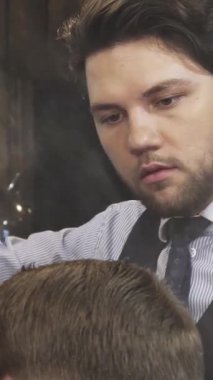 Samimi bir berber dükkanında, odaklanmış, yakışıklı sakallı bir berber erkek müşterilerinin saçlarına ince bir su püskürterek tasarım sürecini hassasiyetle geliştirir. Bu samimi sahne berberleri tımar etme ve sergileme sanatını ön plana çıkarıyor.