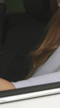 Canlı bir yakın plan fotoğraf, uzun, dalgalı saçlı neşeli bir kadın modern aracında otururken kendine güveni tam bir araba anahtarı tutuyor. Bu görüntü pozitif ve heyecan saçıyor, araba sahibi olmanın heyecanını ve yeni bir hayatın neşesini yakalıyor.