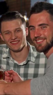 İki neşeli adam, biri şık sakallı, diğeri de modaya uygun tişörtlü, sıcak bir barda buzlu bira içerek kahkahalar atıyorlar. Işıl ışıl gülüşleri ve sıcak, davetkar ambiyansları arkadaşlığın canlı bir sahnesini yaratır.