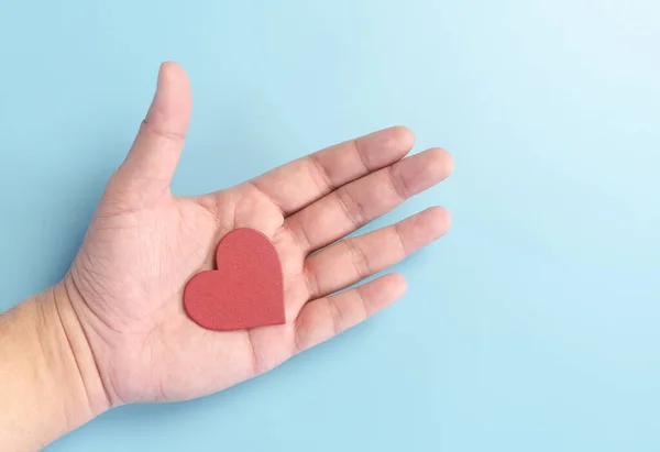 red wooden heart shape piece in human hand