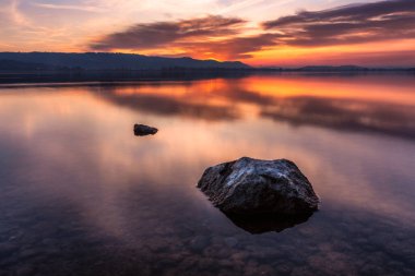 Lake Constance lake shore with stones in the water powerful sunset with beautiful colors in the sky