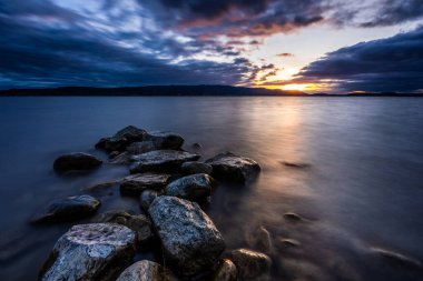 Lake Constance lake shore with stones in the water powerful sunset with beautiful colors in the sky