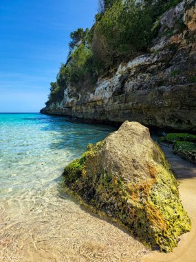 Cala Romantica Mallorca 'da turkuaz suyu ve güneşli uçurumlarla kayalık bir sahil.