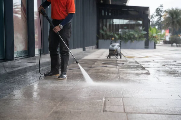 cleaning staff hoses a portable car for washing the concrete floor with high-pressure water jets.