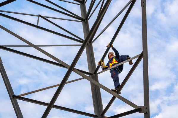 Close up of Workers wearing safety harnesses are working at high voltage pylons for inspection and maintenance at high voltage pylon stations.