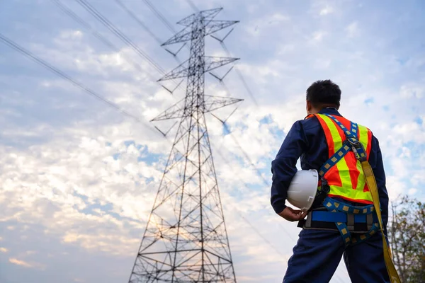 A Technician or Worker holding a safety helmet wear fall arrestor device for worker with hooks for safety body harness. Working at height equipment. at high voltage electricity poles.