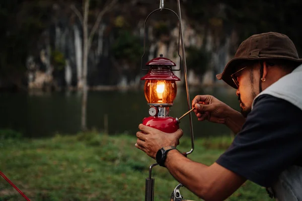 Asian man lanterns are lit Kerosene lamp at the lakeside. Vintage style lantern at night outdoor. Outdoor Camping Concept.
