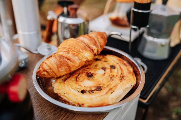 Croissants on stainless steel plate for camping. French tasty picnic. Strawberry pile. Summer Camping.
