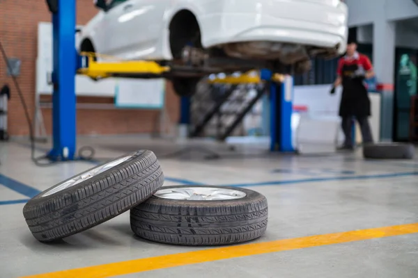Auomobile repair, Used car tires on epoxy floor in auto workshop, Vehicle raised on lift at maintenance station. Check the condition of your tires or change your tires. check up tires.