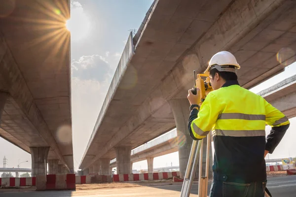 A male surveyor engineers worker use radio communication and making measuring with theodolite on road works. Survey engineer at road construction site, Surveyor equipment. Highway.
