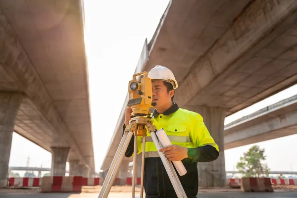 アジアの土木技術者や測量士は 道路建設現場 測量機器で熱心に 高速道路 — ストック写真