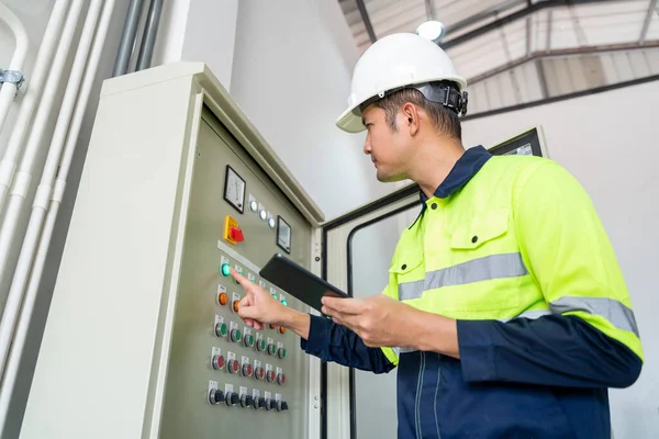 亚洲工程师或电工在工厂用石板对供水系统控制柜进行电气检查 — 图库照片