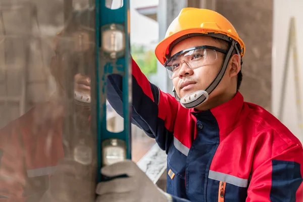 An engineer or inspector wearing a safety gear is inspecting a house by measuring the water level for accuracy. Contractor inspection and construction engineering concept.