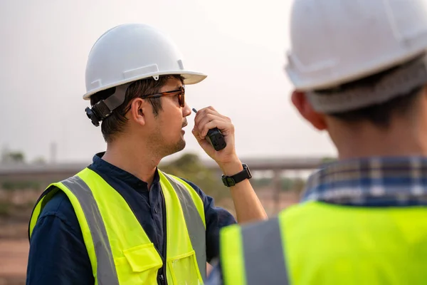 Close-up Architect and Civil Engineer checking work with walkie-talkie for communication to management team in the construction site. Civil Engineer.