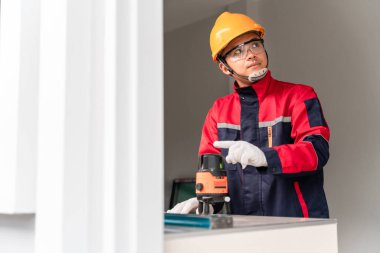 Asyalı mühendisler veya inşaat işçileri inşaat ve onarım veya yenileme çalışmalarından önce beton duvarlardaki doğru ölçümler için çizgi lazer seviyesi araçları kullanıyorlar.