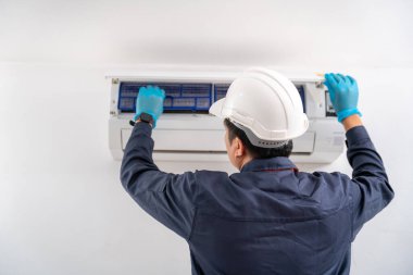 Hava teknisyeni beyaz duvardaki klimayı kontrol ediyor ve tamir ediyor. Klima teknisyeni servis kavramı.