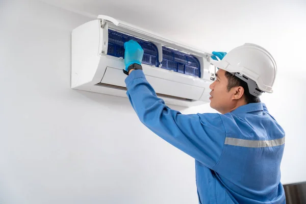 白い壁に青い均一なサービスチェックと修理エアコンを身に着けている航空技術者 エアコン技術者のサービスコンセプト — ストック写真