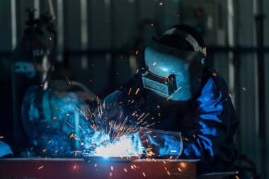 Çelik kaynak fabrikalarında endüstriyel üniforma giyen ve demir maskeli işçiler, ilk konsept endüstriyel güvenlik..