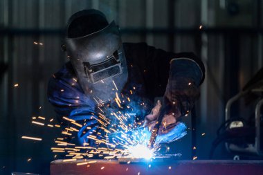 Çelik kaynak fabrikalarında endüstriyel üniforma giyen ve demir maske takan bir teknisyen ya da işçiler önce endüstriyel güvenlik kavramını kullanıyor..