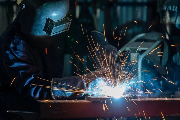 Fabrikanın içinde kaynak makinesi kullanan bir işçi ya da ağır sanayi işçisi. Endüstriyel güvenlik önce gelir.