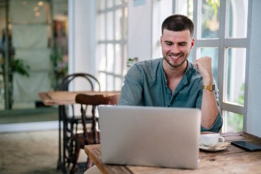 Masada oturan yakışıklı ve başarılı bir serbest çalışan dizüstü bilgisayar. Bağımsız kavram.
