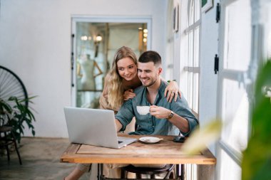 Genç çift iş yerinde dizüstü bilgisayara bakıyor. Çiftler tek bir fikri paylaşır..