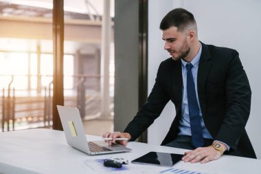 Bir araba satıcısı dizüstü bilgisayar ve kontrol listesi olan oyuncak araba kullanır ve internette kaza durumunda dizüstü bilgisayar kontrolü yapar. Otomobil sigortası kavramı. 