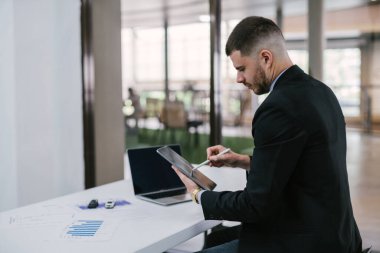 Tablet tutan bir adam ve kontrol listesi olan oyuncak arabalı bir adam. İnternette kaza ihtimaline karşı dizüstü bilgisayarı kontrol edin. Otomobil sigortası kavramı. 