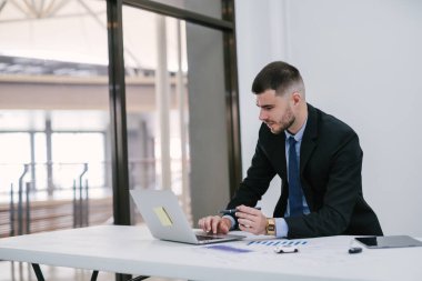 Ofiste çalışan beyaz bir erkek dizüstü bilgisayar kullanıyor. Araba satıcısı ulaşım masraflarını yönetmeyi planlıyor. Galeri ve çevrimiçi satış kavramı.