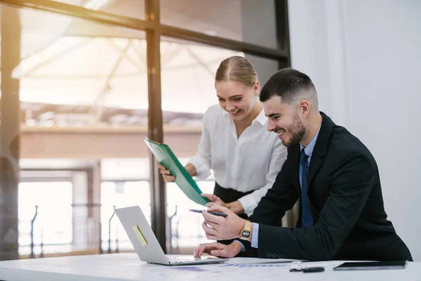 stock image Attractive handsome white businessman sitting at desk with co-worker female holding file document consultant working on laptop computer in office.