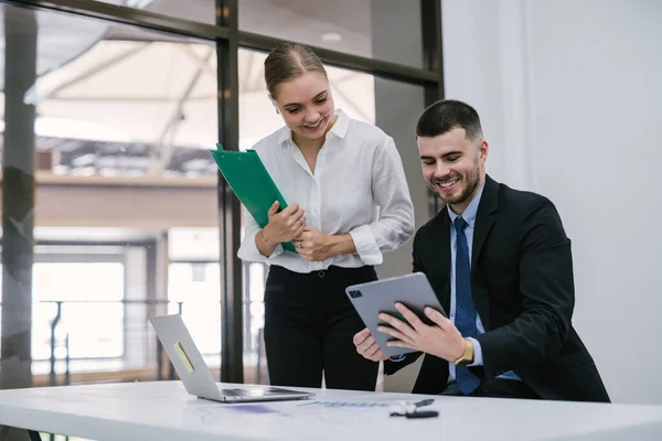 stock image A caucasian young male management manager consultant consulting on financial operations with female colleague using laptop sitting in office
