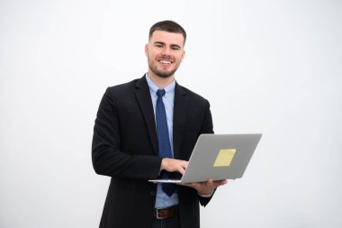 Takım elbiseli bir işadamı ve gülümseyen genç yakışıklı beyaz arka planda dizüstü bilgisayarla kameraya bakıyor..