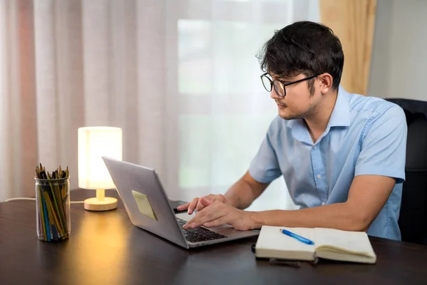 stock image Asian handsome man in glasses working on desk with laptop at home.