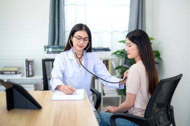 Hastaneden alınan notlarla hastanın kalp atışlarını kontrol etmek için steteskop kullanan Asyalı kadın doktor. İlaçlar. Yaşlı sağlığı. Sağlık ve Tıp Konsepti.