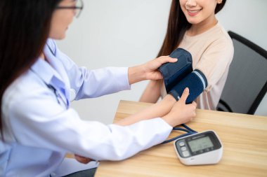 Hastanedeki hastaya kan basıncını dijital sphygmomanometre ile ölçmek için kol bandı takan bir kadın doktor. Tıbbi ve sağlık konsepti.