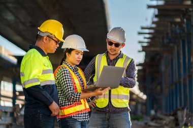 Bir grup profesyonel, inşaat mühendisi, mimar ekspres yol inşaat alanını inceliyor. Yol inşaatındaki dizüstü bilgisayardaki verilerle..