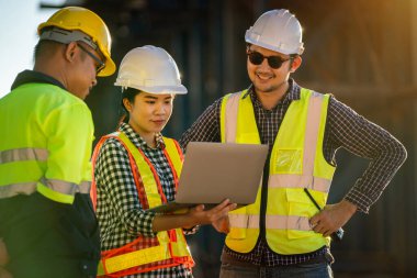 Mimarlar, mühendisler, ustabaşılardan oluşan profesyonel bir ekip otoban inşaatında dizüstü bilgisayarlar üzerinde çalışıyor. Yol yapımının takım çalışması konsepti.