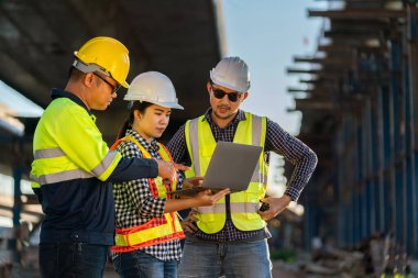Mühendislerden, mimarlardan, inşaat mühendislerinden oluşan profesyonel bir ekip, ortak planın detaylarını tartışmak için inşaat alanında tablet bilgisayar kullanıyor..