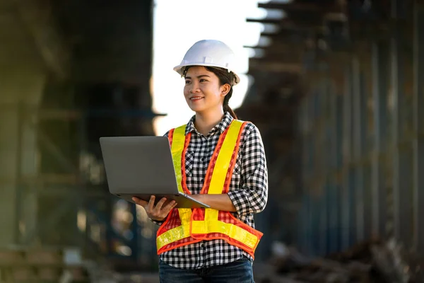 公路建筑工地采用新技术和新型笔记本电脑的亚洲女工程师考试结构 — 图库照片