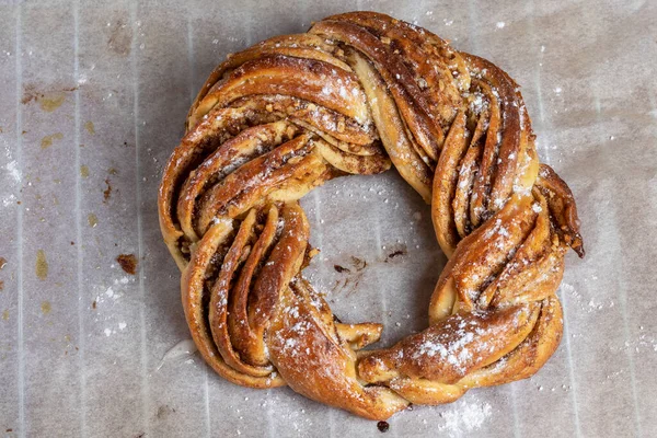 stock image Roscon de reyes Kringle Estonia. Typical Christmas sweet, braided sponge cake with cinnamon, butter, walnuts or almonds and icing sugar. Horizontal photo and selective focus.